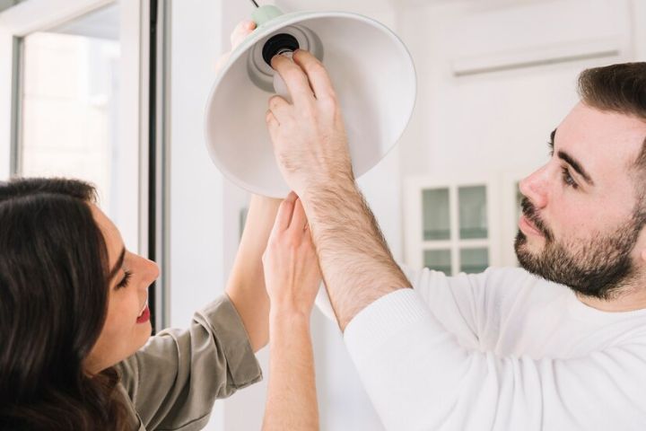 franjas horarios luz: una pareja que tiene contratada la luz con Naturgy colocando una bombilla en una lámpara