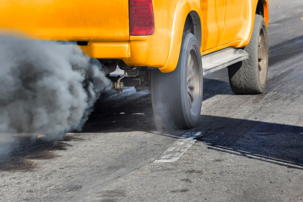 reduccion de huella de carbono: coche echando humo negro por el tubo de escape