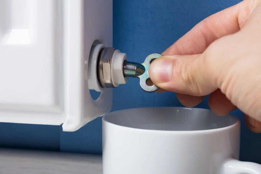 por qué suenan los radiadores de la calefaccion: mano abriendo la llave de los radiadores